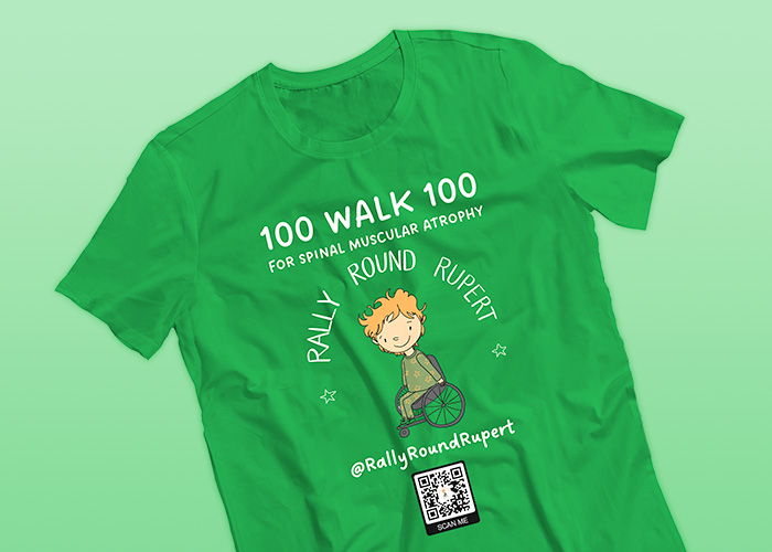 A green t-shirt on a light green background that reads 100 walk 100 for spinal muscular atrophy. It also reads Rally Round Rupert and has a cartoon image of a young fair-haired male wheelchair user